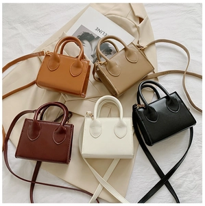 Flat lay of mini leather handbags in five colors on a beige blazer and magazine