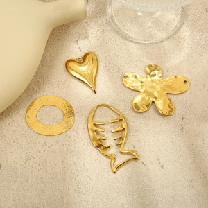 Detailed view of gold stainless steel heart, flower and fishbone jewelry pendants