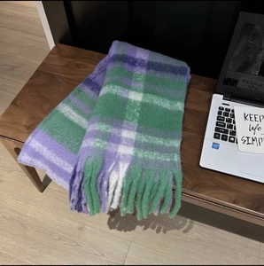 Close-up of thick plaid scarf in purple and green with soft tassel fringe detail