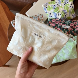 Close-up of a puckered fabric makeup bag with a zipper and simple wish label