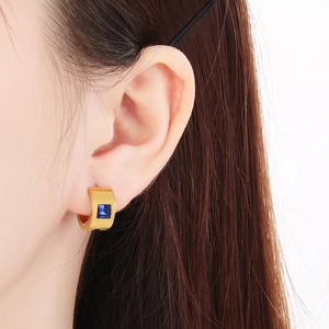 Close-up of golden stainless steel hoop earrings featuring a square blue zircon gemstone