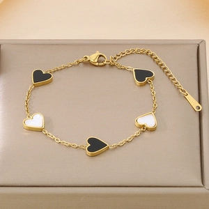 Detail of gold heart link bracelet with black and white shell motifs in a jewelry box