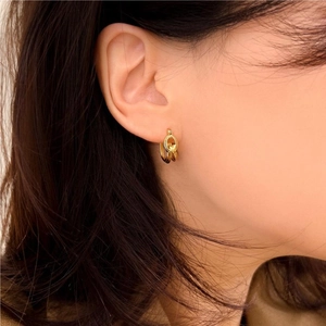 Close-up of elegant gold knot hoop earrings worn by a model for a minimalist style