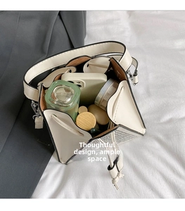 Spacious interior of white triangle bucket bag showing phone and cosmetic storage