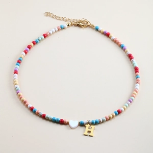 Colorful beaded necklace with a white heart charm and gold H-letter pendant close-up