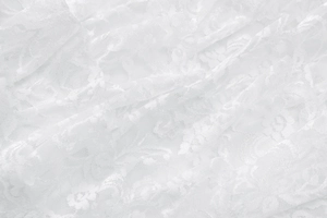 Close-up of white floral lace fabric with delicate mesh texture and soft drapery