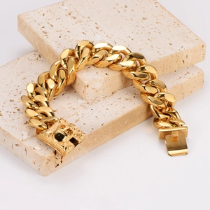 Polished gold Cuban link bracelet with engraved skull clasp on travertine stone pedestals