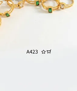 Detailed macro view of 18k gold plated twist rings featuring emerald and clear baguette stones