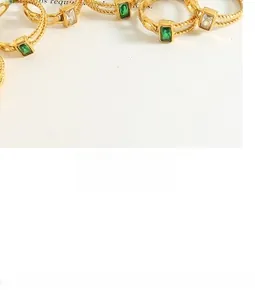 Detailed macro view of 18k gold plated twist rings featuring emerald and clear baguette stones
