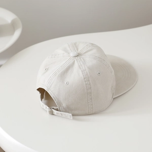 Vue détaillée de la texture de la casquette beige en coton avec sangle réglable au dos