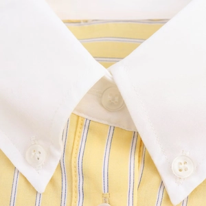 Detailopname van de gele gestreepte overhemdkraag met witte button-down accenten