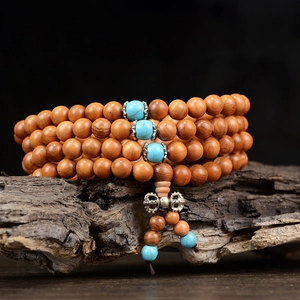 Vue macro d'un chapelet de 108 perles en bois de santal avec des espaceurs turquoise
