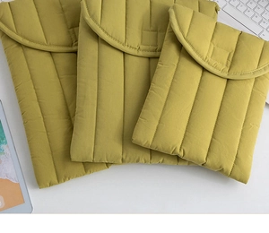 Detailed view of mustard yellow quilted laptop sleeves in three sizes on a white desk