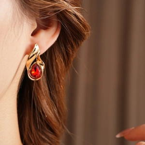 Primo piano di orecchino vintage dorato con pietra rossa a goccia su una modella