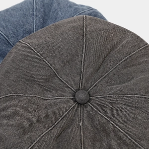 Close-up of denim beret hats showing top stitching detail and round covered button