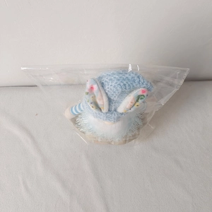 Detail of Easter gnome plush toy with blue rabbit ears hat in transparent packaging
