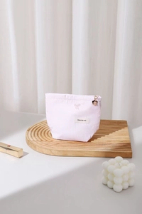 Détail d'une trousse à maquillage rose avec broderie nœud et pendentif fleur dorée