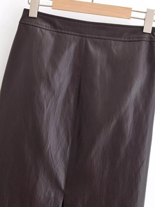 Détail d'une jupe en similicuir marron foncé avec taille ceinturée et texture mate