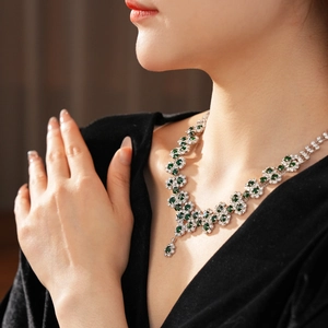 Detail of emerald and diamond sunflower pendant necklace on a model's neck