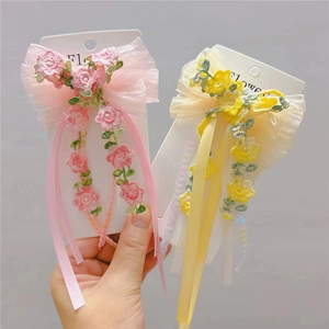 Detail of floral embroidery on mesh hair clips with delicate ribbons for girls