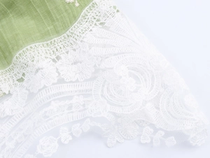 Macro shot of green pleated fabric and delicate white floral lace detailing