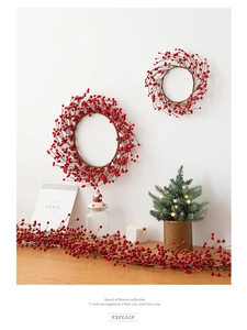 Detailed view of red berry Christmas wreaths and garland on a festive wooden table