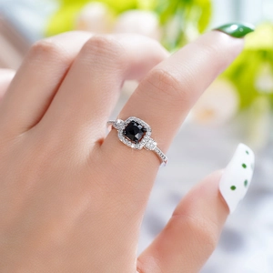 Macro shot of a silver ring with a square black stone and pavé zircons worn on finger