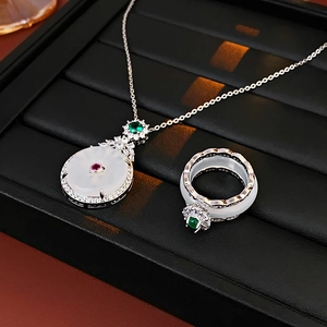 Detailed close-up of white jade jewelry set with green gemstones on black display