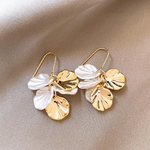 Detailed shot of vintage gold petal earrings with pearls on champagne silk fabric
