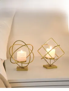 Detailed view of geometric gold metal candle holders with lit white pillar candles