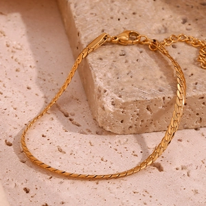 Polished 18K gold plated stainless steel NK chain bracelet on a textured stone surface