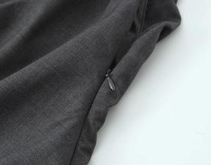 Dettaglio di un top grigio scuro con spalline imbottite e cerniera invisibile sul retro