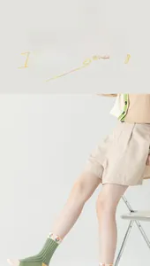 Close-up of green crew socks with orange tulip pattern and beige cotton texture shorts