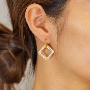 Close-up of minimalist gold square stud earrings with pave-set crystals on a model