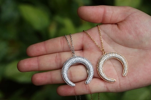 Close-up of crescent moon pendants with pave-set zircons in silver and gold tones
