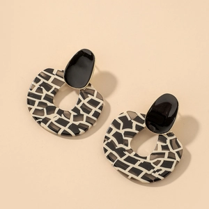 Detailed close-up of retro geometric zebra print acrylic drop earrings with gold trim