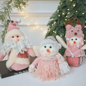 Three pink and white Christmas plush ornaments featuring Santa and snowmen figurines