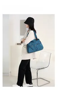 Close-up of blue nylon tote bag with front zip pockets and wide black shoulder strap
