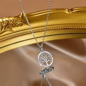 Detail of silver tree of life hollow pendant necklace reflected on vintage mirror
