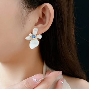 Détail de la boucle d'oreille fleur en résine avec gemme bleue et nacre sur modèle