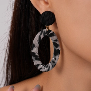 Close-up of leopard print fabric earrings worn by model showing texture and oval design