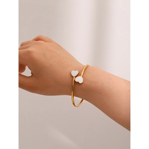 Detailed view of an 18k gold plated open bangle featuring double white enamel hearts on wrist