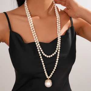 Detail of elegant double-layer faux pearl necklace with gold floral pendant on model