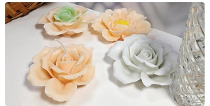 Top view of handmade rose aromatherapy candles in various shapes on a white table