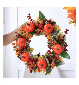 Close-up of autumn wreath with orange pumpkins, red berries, and golden maple leaves