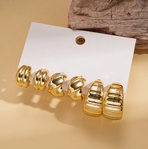 Detail of three-pair gold geometric C-shaped hoop earring set on white display card