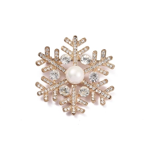 Macro shot of sparkling snowflake brooch with gold plating, rhinestones, and central pearl