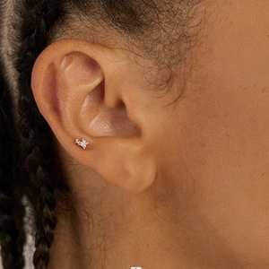 Close-up of minimalist stainless steel cartilage stud with chain and tiny gemstone on ear