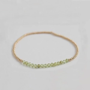 Detail of beaded bracelet with faceted olive green stones and polished gold metal beads