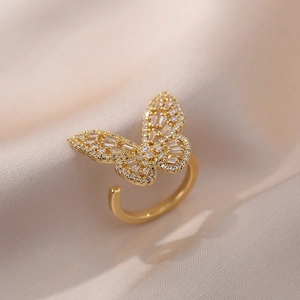 Macro shot of gold butterfly ring with zircon stones on soft beige fabric background
